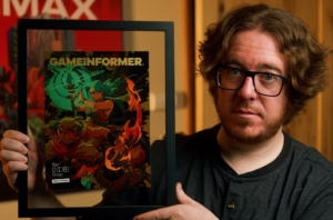 Headshot of Game Inform Executive Editor, Kyle Hilliard. In the photo he's holding a framed issue of the Game Informer magazine.