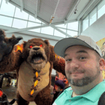 A headshot of Jason Fanelli standing in front of a bear monster with red eyes.